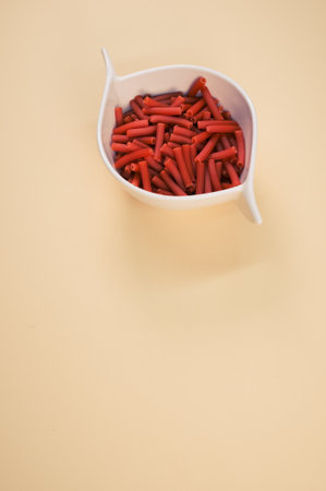 A bowl of dry macaroni pasta isolated on a beige background with free space for textの写真素材