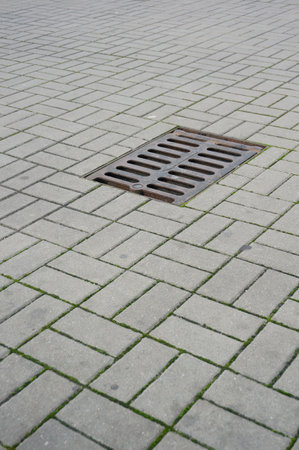 A vertical shot of a manhole on the sidewalk with stone tilesの写真素材
