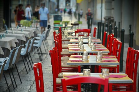 A closeup shot of arranged tables of an outdoor restaurant in a city centerの写真素材
