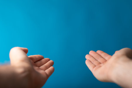 A male showing outstretched hands with open palms on a blue backgroundの写真素材