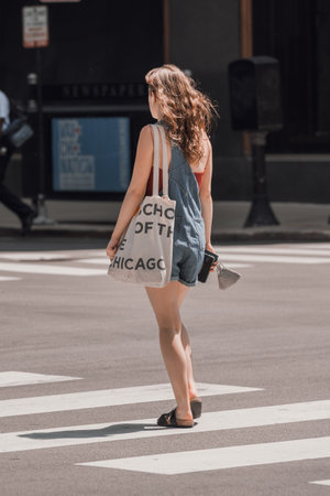 A vertical shot of a young stylish female crossing the street