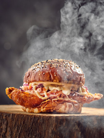 A vertical closeup of a chicken burger on the stump with dark blurred backgroundの写真素材