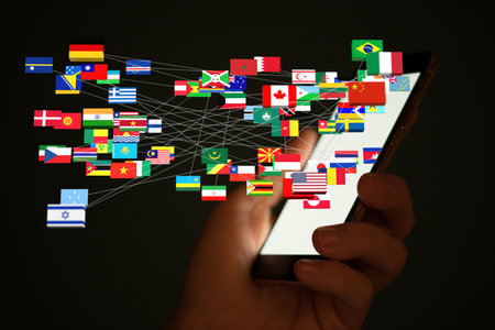 A male's hand holding a smartphone on which is a 3D rendering of international flagsの写真素材