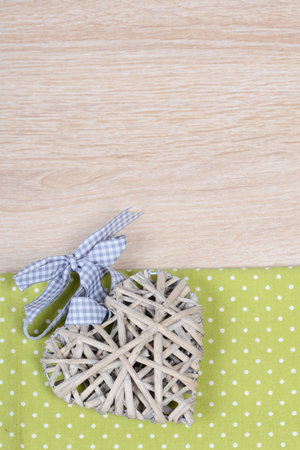 A heart-shaped necklace on a green paper on a brown table surfaceの写真素材