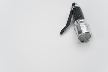 A closeup shot of a small black-silver flashlight isolated on a white backgroundの写真素材