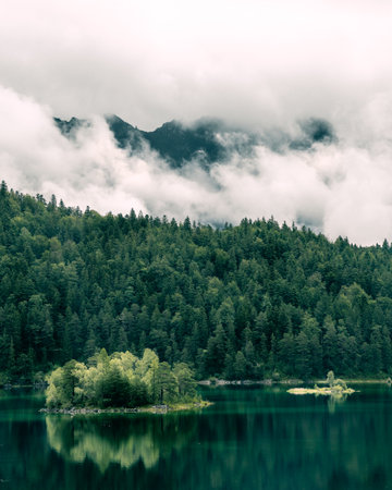 Lake Eibsee in Bavaria with clouds and mountain peaks in the background. island in the front.の写真素材