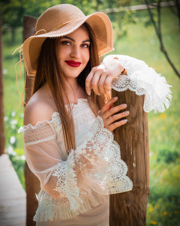A beautiful shot of a female model in a white dress posing on a lane surrounded by treesの写真素材