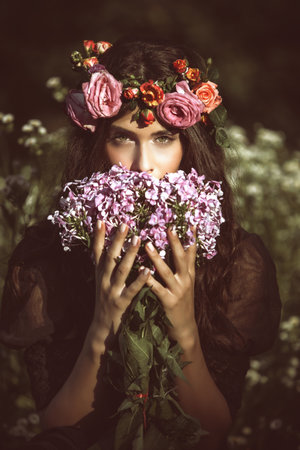 beauty portrait of young woman with flowers in field summer dayの写真素材