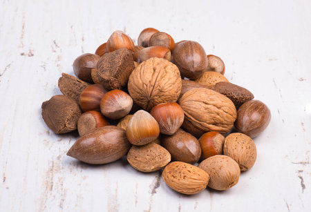 Mix of nuts on a textured background, empty copy space for text, hazelnuts, walnuts, peanuts