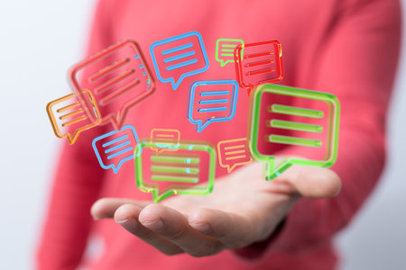 A 3D rendering of colorful speech bubbles hovering over a man's handの写真素材