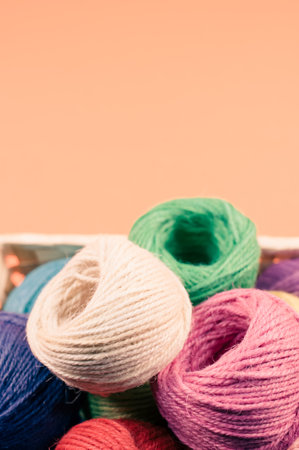 A vertical shot of a basket of colorful balls of yarn on an orange surfaceの写真素材