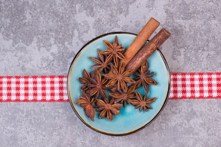 Satr anise and cinnamon on a blue plate on a grey textured background, spices for christmas, winter season, empty copy space for textの写真素材