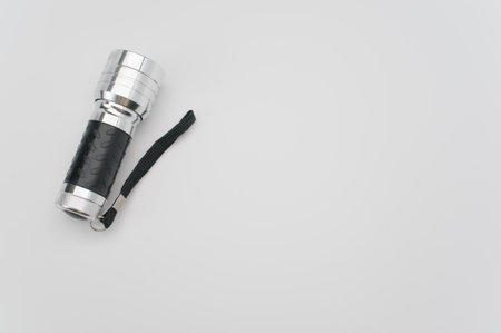 A top view of a small black-silver flashlight isolated on a white background