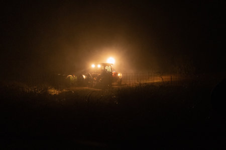 A street lamp and a tractor in a field during nighttime