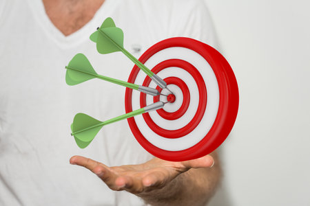 A 3D rendered target with darts hovering over a man's handの写真素材
