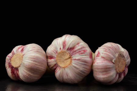 A closeup of three garlic bulbs isolated on a black background