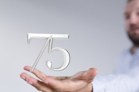 A digital 75 years anniversary award in a handの写真素材