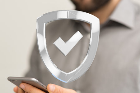 A silver 3d rendered shield sign hovering over a smartphone in a man's handの写真素材