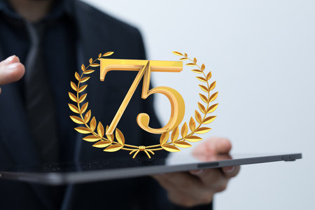 A digital 3d gold number 75  logotype for the anniversary, floating out of the tabletの写真素材