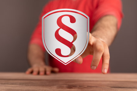 A closeup of a man touching a rendering of a paragraph sign on a shield - justice and insurance conceptの写真素材