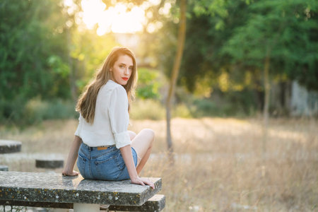 A young attractive Spanish woman wearing shorts with a white shirt in a park on a sunny dayの写真素材