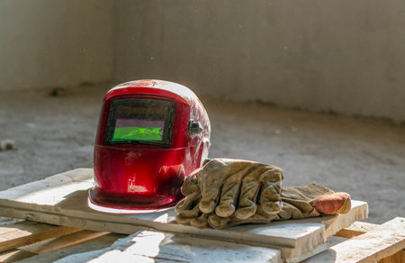 Protective equipment of the working welder: welding helmet and leather gloves. Lie on a wooden surface.の写真素材