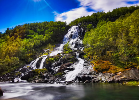 A scenic waterfall on a sloped mountain with lush treesの写真素材
