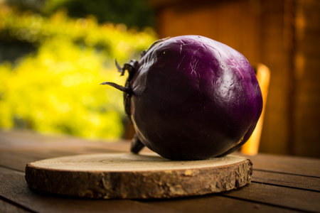 A closeup shot of an eggplant on a small wooden round cutting boardの写真素材
