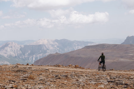 A beautiful shot of a cycler on a mountain with cloudy skies in the backgroundの写真素材
