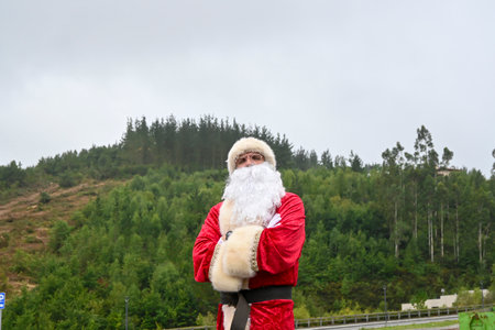 A young male in a Santa Claus suit doing a funny pose outdoorsの写真素材