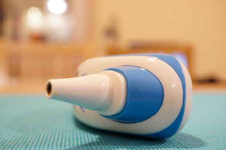 A shallow focus shot of an ear thermometer isolated on the green backgroundの写真素材