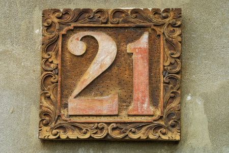 An aged wooden address sign with twenty-one written on it