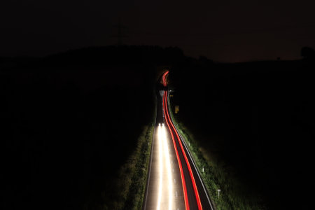 A landscape of cars driving on the road with long exposure surrounded by fields at nightの写真素材