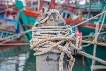 Rope bollard jetty or rope tied up on a pole on a wooden dock or Boat rope tied to a wooden post on a floating boat railingの写真素材
