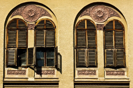 The old wooden windows on a brownish wall of a buildingの写真素材