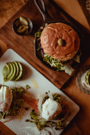 A top view of a delicious appetizing burger with beef and sandwiches with salmon and eggs on a tableの写真素材