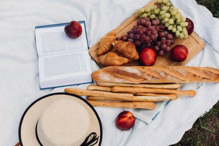 A still life with croissants, baguette, fresh fruits, summer hat and bookの写真素材