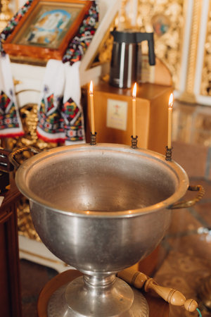 Three burning candles on a baptismal font in the churchの写真素材