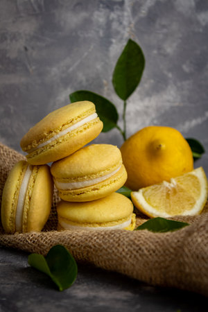 A closeup of the fresh sweet macaroons on the brown fabric with lemonsの写真素材