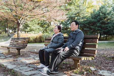 A Korean elderly couple sitting on a bench in a park in autumn in South Koreaの写真素材