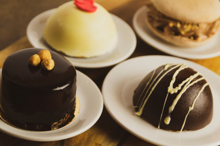 A closeup shot of pastries with various decorations on white platesの写真素材