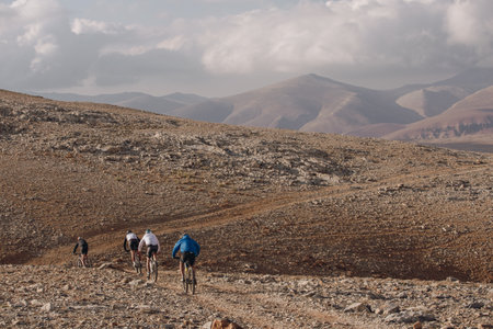 A beautiful shot of cyclers on a mountain with cloudy skies in the background