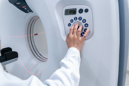 A doctor's hand manipulating the buttons of a high end Computerized Tomography scanner