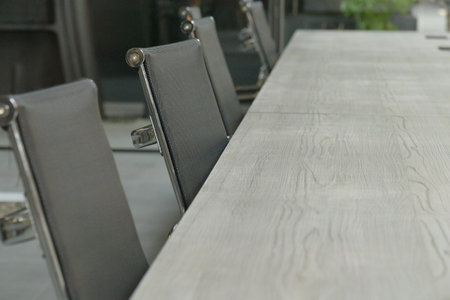 A closeup of a meeting table with empty black seats.