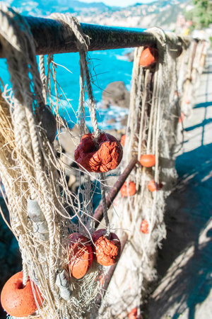 A closeup of tangled fishing nets hanging on a railing at a fishing villageの写真素材