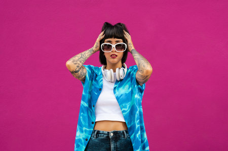 A sexy young woman with tatted arms from Spain in a vibrant blue shirt posing in a studioの写真素材