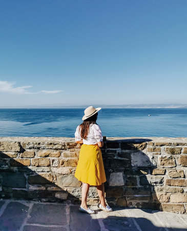 Young woman standing on path overlooking adriatic sea in Piran, Slovenia.の写真素材