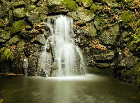 A beautiful shot of a waterfall surrounded by rocks covered in green