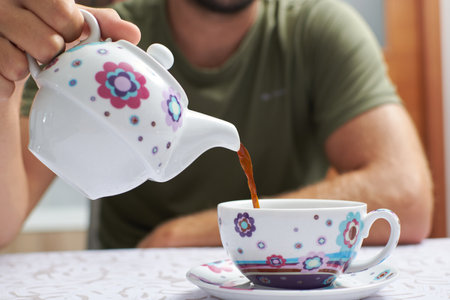 A closeup shot of a male's hand pouring coffee into a cup