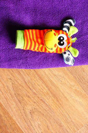 A vertical shot of a colorful sock with a cartoon giraffe face isolated on the purple blanketの写真素材